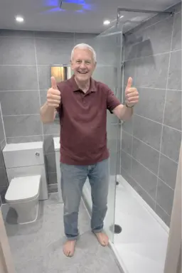 Delighted client showing finished bathroom renovation with clean modern design 
